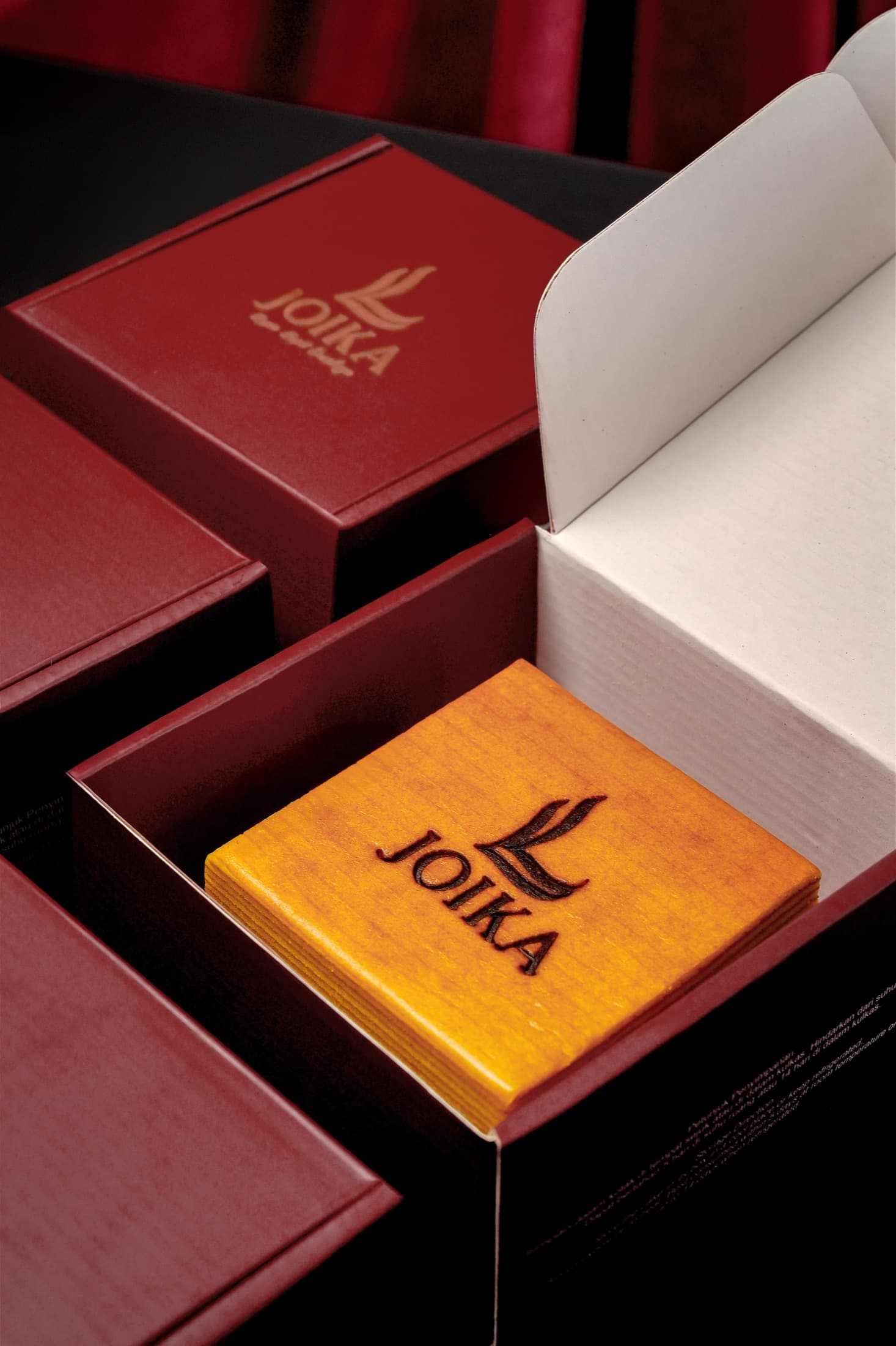 Lapis Legit Joika di dalam kotak merlot dengan beberapa kemasan tertata di belakangnya.